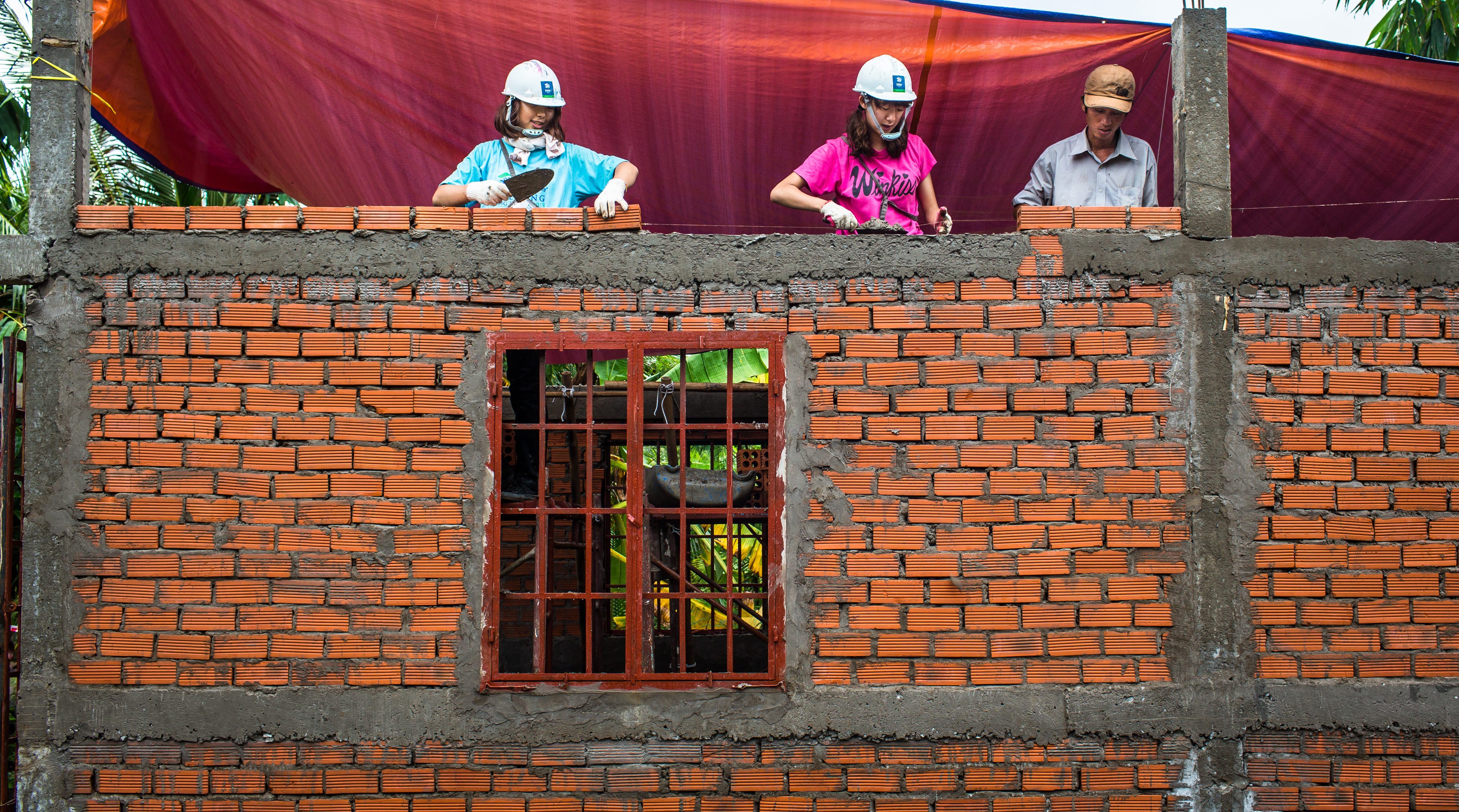 3 people placing bricks in Vietnam on a build day