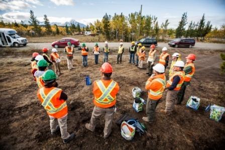 Volunteer standing in a circle with safety vests and hard hats