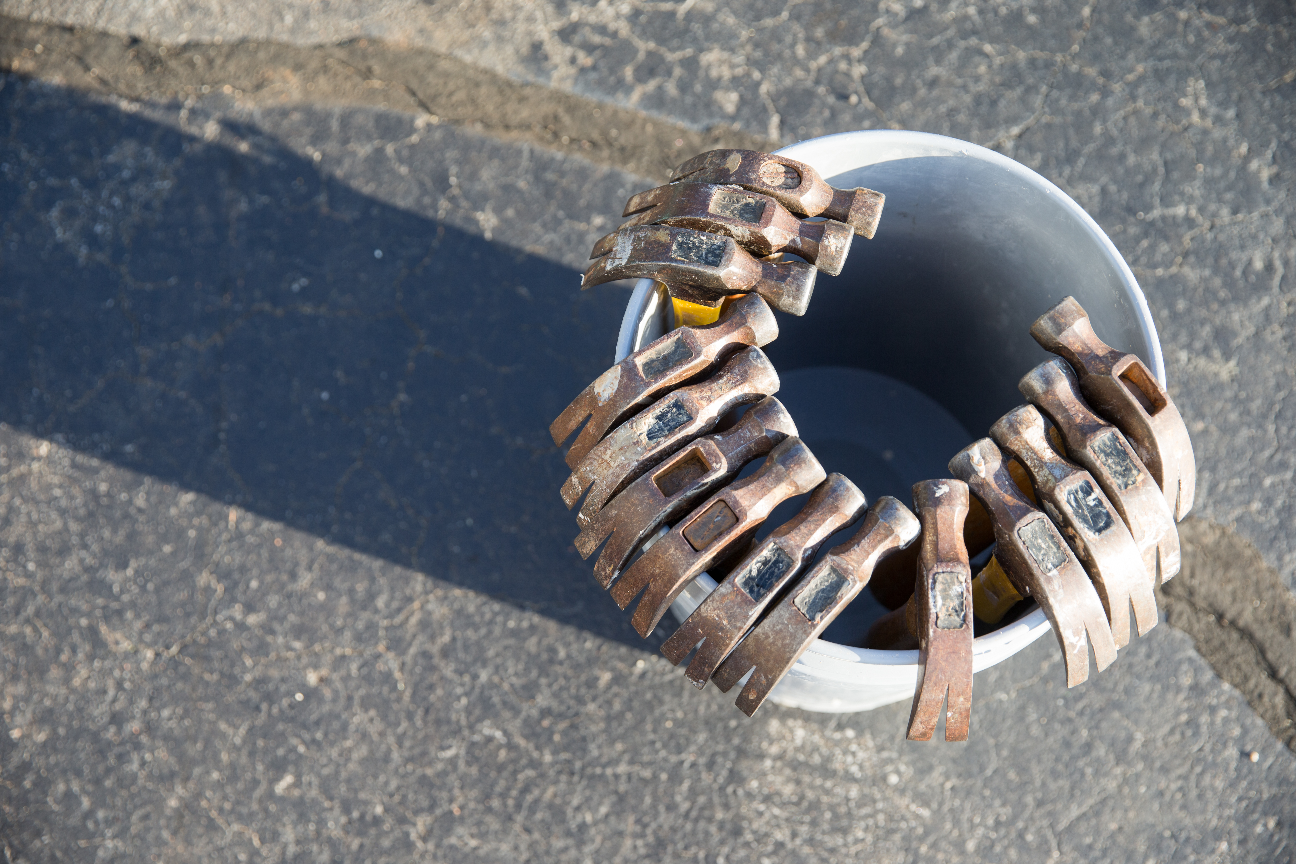 13 hammers standing upright side by side in a bucket