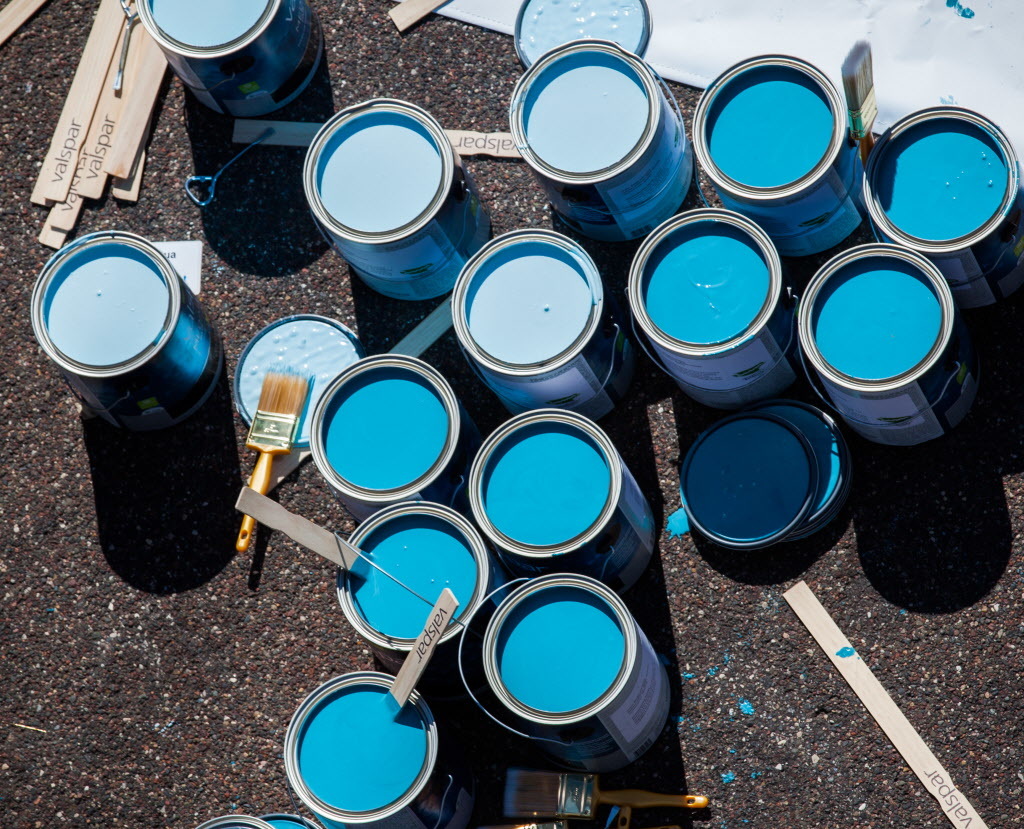 Multiple paint cans opened, filled with light blue and teal blue paint