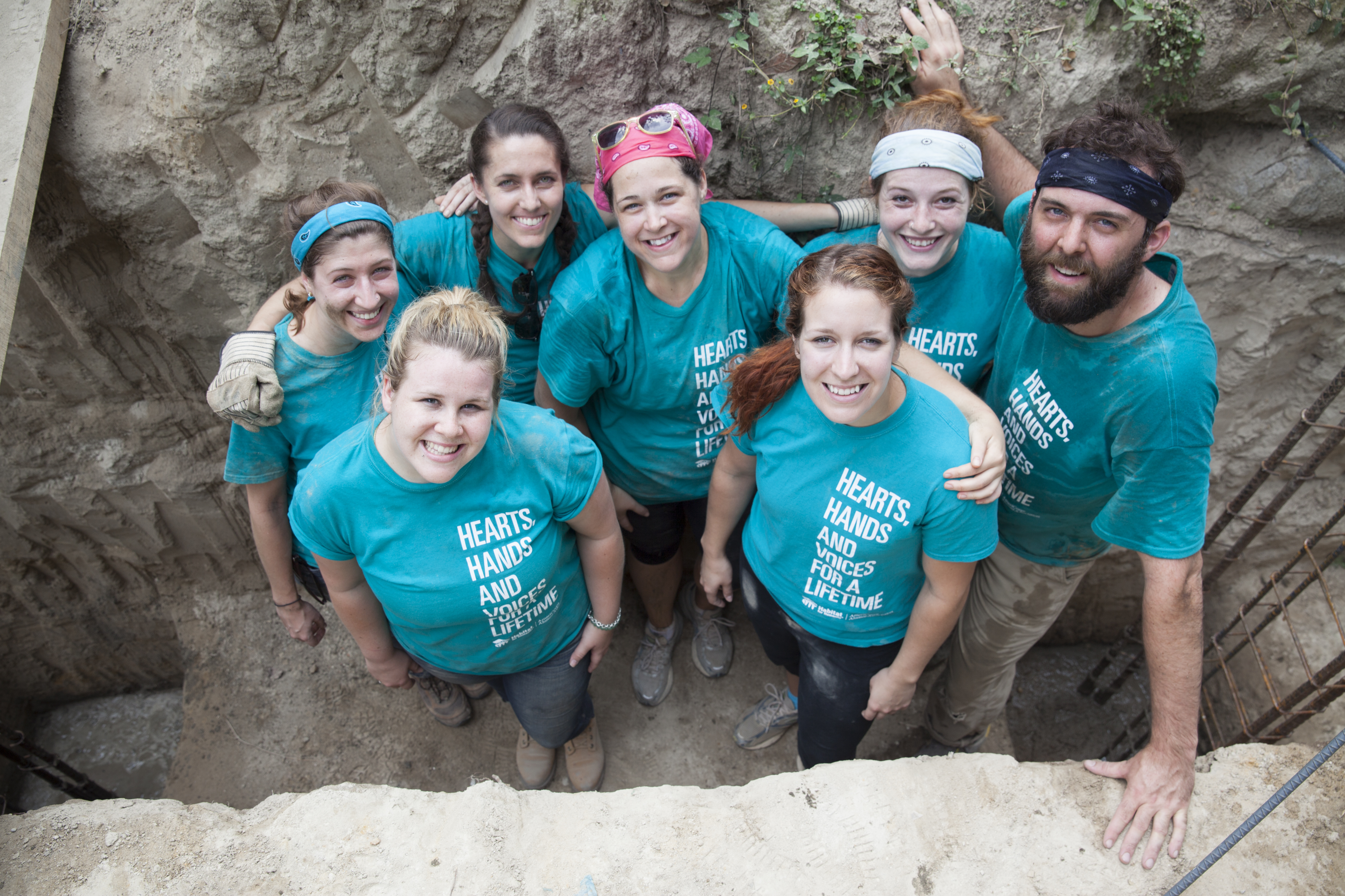 6 women and 1 man looking up towards camera smiling